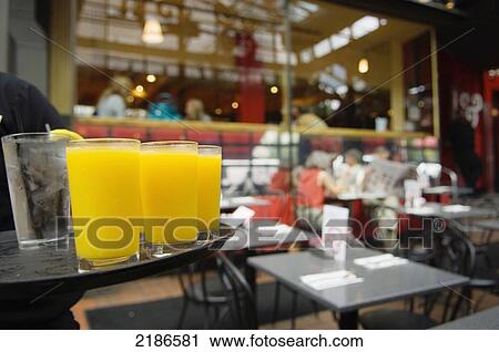 Stock Image - USA, Waiter serving orange juice to customers at Kramer books and aferwords. This is a local instition offering a wide selection of books a bar and live music; Washington DC. Fotosearch