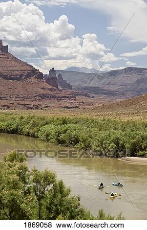 Stock Photo - Utah, United States Of America; Three Kayakers Floating Down The Colorado River East Of Moab, With The Fisher Towers In The Distance. Fotosearch