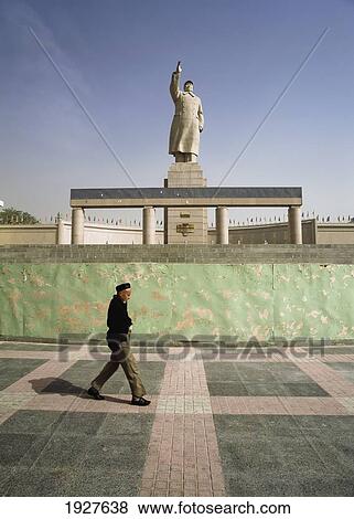 Stock Photo - Uyghur Man Walking Under Statue Of Mao. Fotosearch
