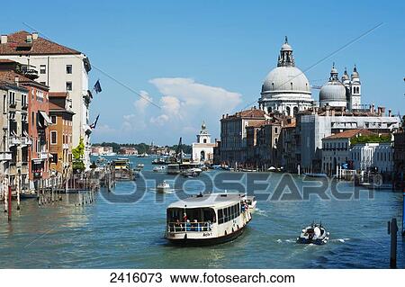 Stock Image - Vaporatto (buses) on the Grand Canal, Basillica Santa Maria Della Salute in the background; Venice, Italy. Fotosearch