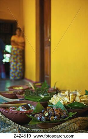 Stock Photo - Variety of food dishes on a table with a woman standing in the background; Ulpotha, Embogama, Sri Lanka. Fotosearch