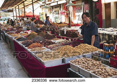 Stock Photograph - Vendor Standing By Food At A Market; China. Fotosearch