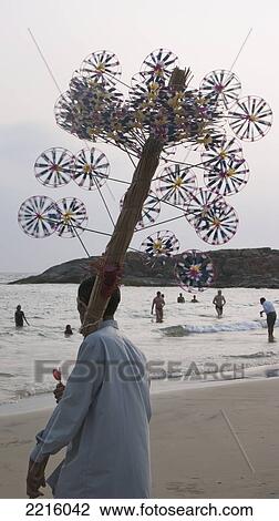 Stock Image - Vendor With Wind Toys On Kovalam Beach, Kovalam, Kerala, India. Fotosearch