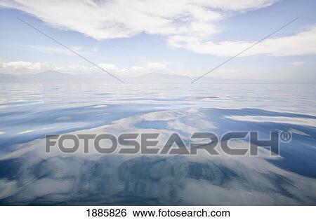 Stock Photograph - Very Calm Waters In The Mediterranean Sea With The Coastline And Clouds In The Background. Fotosearch