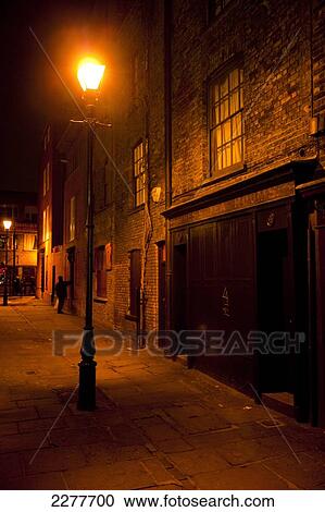 Stock Image - Victorian street lamp lights streets of East London at night; London, England. Fotosearch