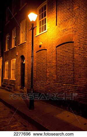 Stock Photograph - Victorian street lamp lights streets of East London at night; London, England. Fotosearch