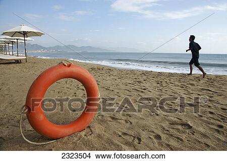 Vietnam, Life Preserver On Beach With Jogger In Background; Nha Trang View Large Photo Image Picture - Vietnam, Life Preserver On Beach With Jogger In Background; Nha Trang. Fotosearch