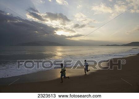 Stock Image - Vietnam, People running along beach at sunset; Nha Trang. Fotosearch