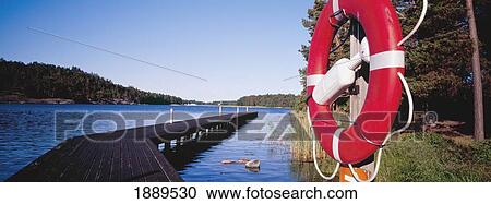 Stock Image - View Across Water And A Pier On Uto Island With A Life Preserver In The Foreground.. Fotosearch