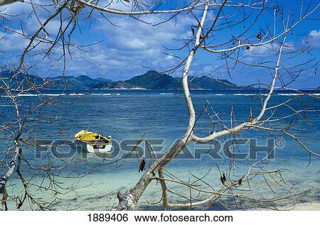 Stock Photograph - View Across Water With A Boat At Praslin On La Digue Island.. Fotosearch