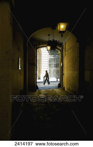 View down a dark corridor to a pedestrian walking by in the street; Barcelona, Spain View Large Photo Image Stock Photo - View down a dark corridor to a pedestrian walking by in the street; Barcelona, Spain. Fotosearch