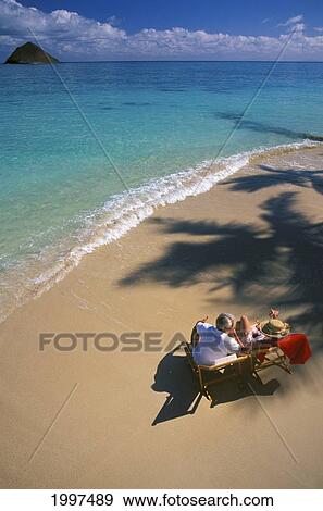Stock Photo - View From Above, Senior Couple Shoreline With Palm Shadows, Turquoise Ocean, Island Background. Fotosearch