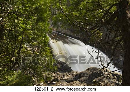 View of a river waterfall through the forested rocky shoreline; Ontario, Canada View Large Photo Image Stock Image - View of a river waterfall through the forested rocky shoreline; Ontario, Canada. Fotosearch