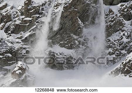 Stock Photo - View of an avalanche falling down steep cliff walls on a mountain during winter, New Zealand. Fotosearch