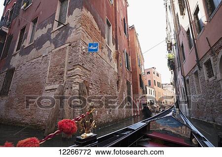 Stock Image - View of buildings along a narrow canal from a gondola; Venice, Italy. Fotosearch