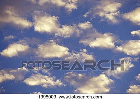 Stock Image - View Of Clouds In Blue Sky, With Slight Sunlight. Fotosearch