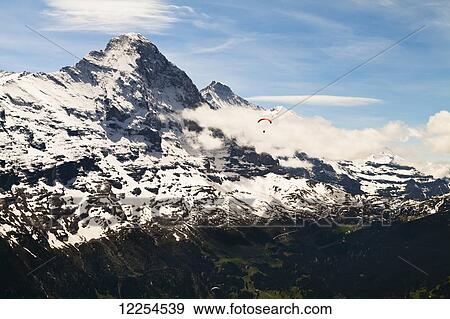 Stock Photo - View of Eiger and Monch from First with paraglider; Grindelwald, Bernese Oberland, Switzerland. Fotosearch