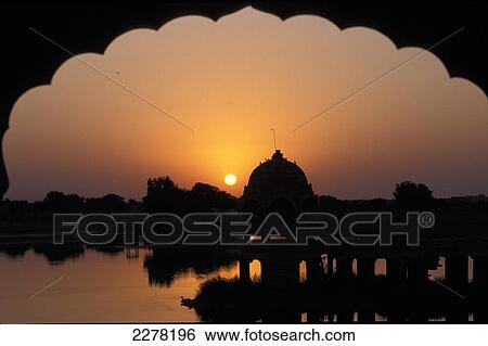 Stock Photograph - View of Gadi Sagar Tank through archway at sunrise; Jaisalmer, Rajasthan, India. Fotosearch