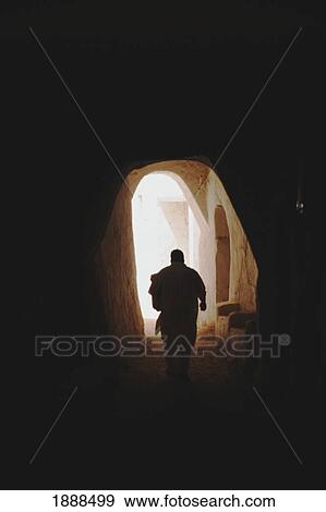 Stock Photo - View Of Man Walking Down Alleyway With Archway. Fotosearch