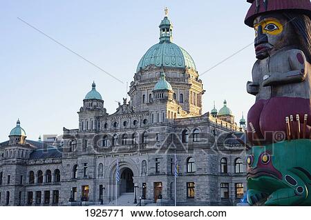 Stock Image - View Of Parliament Buildings & Totem Pole; Victoria, British Columbia, Canada. Fotosearch