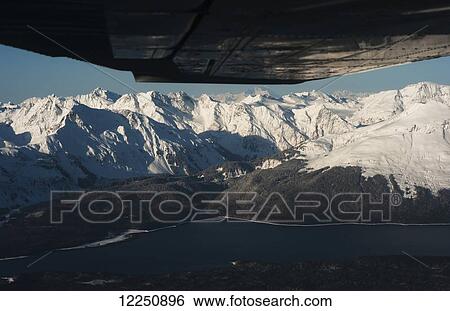 Stock Photograph - View of snow covered mountains from an airplane window; Juneau, Alaska, United States of America. Fotosearch