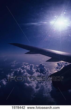 Stock Image - View Of Sun Sky And Clouds From Window Of Airplane, Wing In View.. Fotosearch