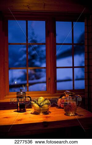 View out of the window of a Brekke rental cabin in winter with food and drink on the dinner table with warm orange light; Ortnevik, Sognefjord, Norway View Large Photo Image Stock Photograph - View out of the window of a Brekke rental cabin in winter with food and drink on the dinner table with warm orange light; Ortnevik, Sognefjord, Norway. Fotosearch