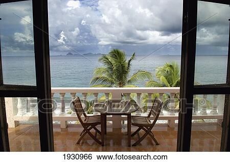 View Through A Doorway Of A Terrace With A Table And Chairs At Petite Anse Hotel. Storm Clouds Gather Over The Ocean; Grenada, Caribbean View Large Photo Image Stock Photograph - View Through A Doorway Of A Terrace With A Table And Chairs At Petite Anse Hotel. Storm Clouds Gather Over The Ocean; Grenada, Caribbean. Fotosearch