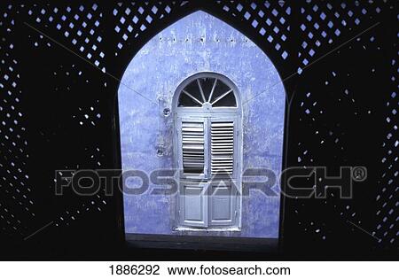 Stock Image - View Through Arched Window To Purple Wall And Shutters. Fotosearch