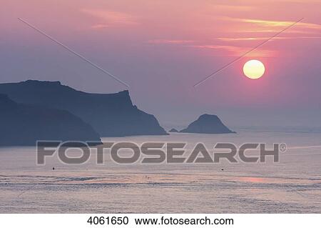 Stock Image - View towards Skomer Island at sunset, near Martin's Haven from Pembrokeshire Coast Path; Wales. Fotosearch