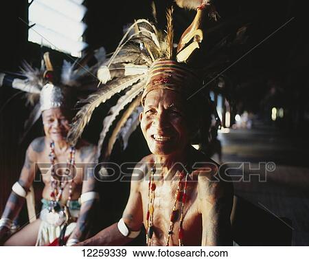 Stock Photo - Village men wearing traditional dress in river longhouse; Sarawak. Fotosearch