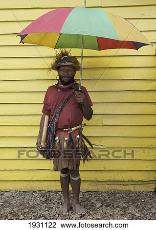 Villager standing under an umbrealla against a yellow building, Mount Hagen, Papua New Guinea., Mount Hagen, Papua New Guinea. View Large Photo Image Stock Image - Villager standing under an umbrealla against a yellow building, Mount Hagen, Papua New Guinea., Mount Hagen, Papua New Guinea.. Fotosearch
