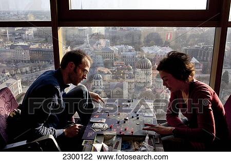 Stock Image - Visitors play a board game on the 26th floor of the Reval Hotel Skyline Bar, at sunset, Riga, Latvia.. Fotosearch