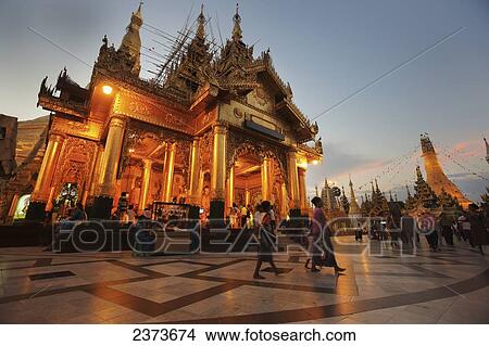 Picture - Visitors walk around Shwedagon Pagoda at sunset; Yangon, Burma. Fotosearch