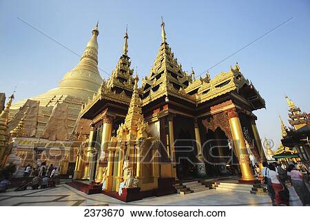 Stock Image - Visitors walk around Shwedagon Pagoda at sunset; Yangon, Burma. Fotosearch
