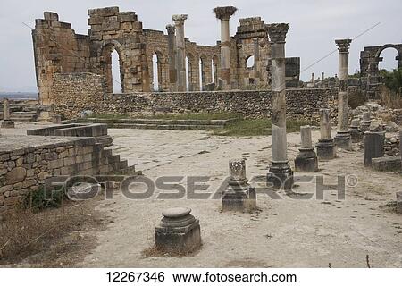 Stock Photograph - Vista across the ruins incorporating Roman arches and pillars carved out of stone; Volubilis, Mauritania, Morocco. Fotosearch