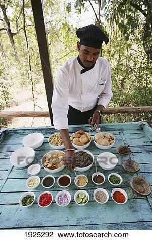 Stock Image - Waiter Setting Out Buffet At Outdoor Table, Madhya Pradeshi, India. Fotosearch