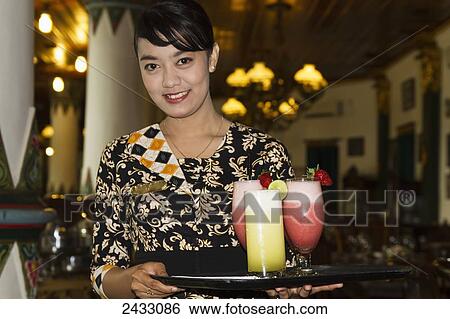 Waitress holding drinks at the Sekar Kedaton Restaurant, Yogyakarta, Java Island, Indonesia View Large Photo Image Stock Photograph - Waitress holding drinks at the Sekar Kedaton Restaurant, Yogyakarta, Java Island, Indonesia. Fotosearch