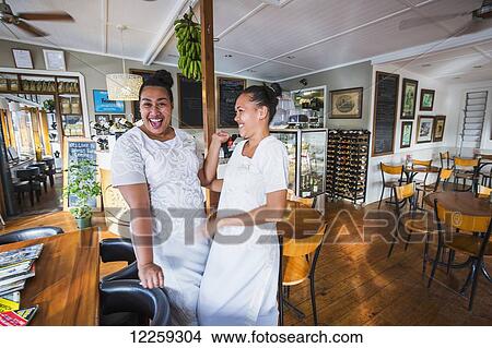 Picture - Waitresses sharing a laugh at the popular Friends Cafe; Tongatapu, Tonga. Fotosearch