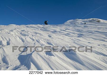 Stock Image - Walker going through heavy snow (in sastrugi pattern) up Beinn Respiol, Ardnamurchan peninsula; Highlands, Scotland. Fotosearch