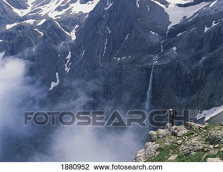 Stock Image - Walker Looking Over Waterfall At Cirque De Gavarnie. Fotosearch