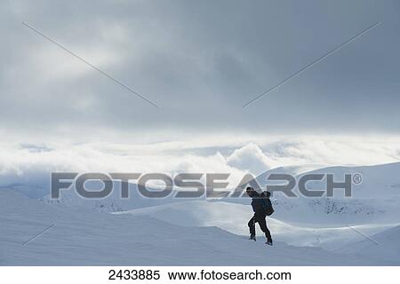 Stock Photography - Walker on snowy, winter walk ascending Geal Charn, near Laggan; Scotland. Fotosearch