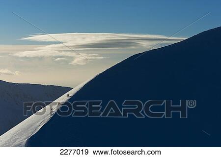 Stock Photo - Walkers climbing snowy ridge of Sgorr Dhearg in winter near Glen Coe; Highlands, Scotland. Fotosearch