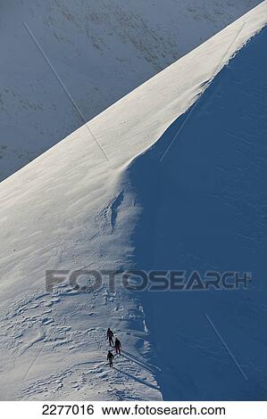 Stock Photograph - Walkers climbing snowy ridge of Sgorr Dhearg in winter near Glen Coe; Highlands, Scotland. Fotosearch