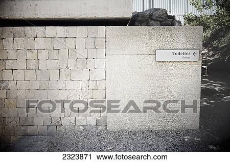 Stock Image - Washroom sign on a white stone wall; Vaison-la-Romaine, France. Fotosearch