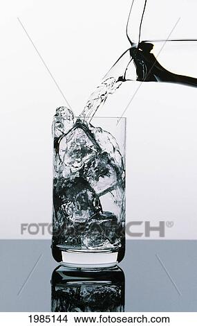 Water Being Poured From A Pitcher Into Tall Glass Filled With Ice Cubes. View Large Photo Image Picture - Water Being Poured From A Pitcher Into Tall Glass Filled With Ice Cubes.. Fotosearch