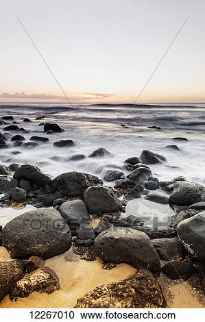 Water washing over rocks along the shore at sunset; Wainiha, Kauai, Hawaii, United States of America View Large Photo Image Stock Image - Water washing over rocks along the shore at sunset; Wainiha, Kauai, Hawaii, United States of America. Fotosearch