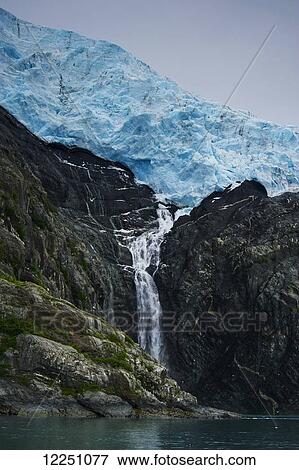 Stock Photo - Waterfall flowing off a glacier; Alaska, United States of America. Fotosearch