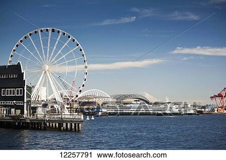 Stock Image - Waterfront view with The Great Wheel, Puget Sound Ferries, Professional Football and Baseball Stadiums, and Mount Rainier, Seattle, Washington, USA. Fotosearch