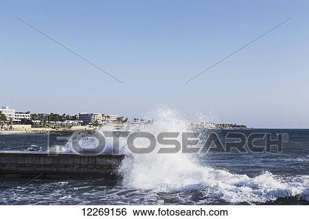 Wave crashing on a pier with buildings along the coast; Paphos, Cyprus View Large Photo Image Stock Photograph - Wave crashing on a pier with buildings along the coast; Paphos, Cyprus. Fotosearch